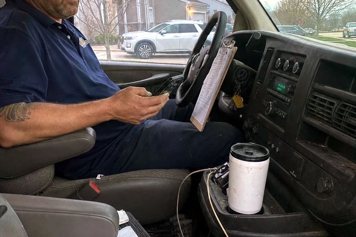 An HVAC technician sitting in his service van at dusk, checking his phone after a job.